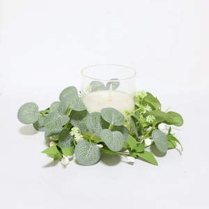 Close-up of artificial eucalyptus wreath with white flowers around a glass candle holder