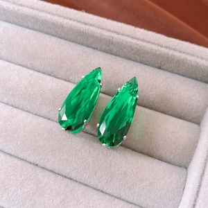 Detail of emerald green pear-cut zircon earrings set in silver metal on velvet box