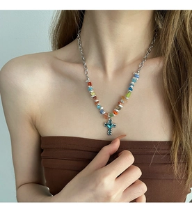 Close-up of colorful stone beads and a blue gemstone cross pendant on a silver necklace