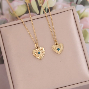 Golden heart necklaces with blue zircon pendants showcased in a pink jewelry box
