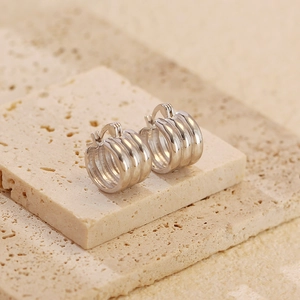 Macro shot of silver multi-layered hoop earrings on a textured stone display pedestal