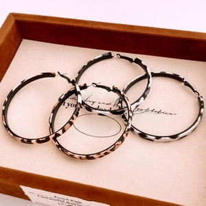 Detail of leopard and zebra print hoop earrings in a wooden jewelry display tray