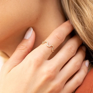 Close-up of stylish triple-layered gold wave ring worn on model's middle finger