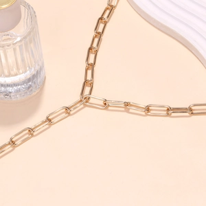 Detailed view of the gold paperclip link chain necklace on a white ceramic tray