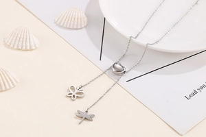 Détail du collier en Y argenté avec curseur cœur, pendentifs papillon et libellule