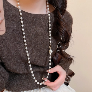 Vue détaillée du long collier de perles baroques avec chaîne dorée sur pull noir