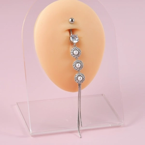 Detail of silver belly ring with zircon, pearl, and long tassels on a silicone model