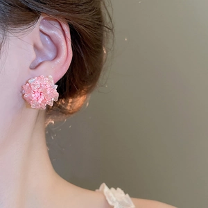 Nahaufnahme von rosa Kristall-Ohrsteckern in Blumenform getragen von einem Modell