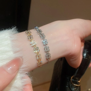 Close-up of gold and silver flower bracelets with zircon inlay on a model's wrist