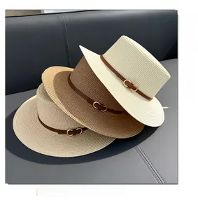 Close-up of three woven flat-top straw hats with leather bands and gold buckles