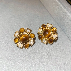 Detailed close-up of vintage flower earrings with amber cat-eye stones and small pearls