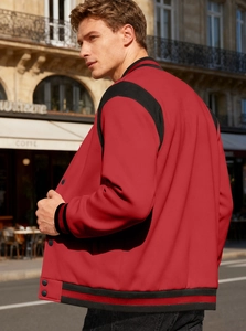 Outdoor street view of red and black varsity jacket with striped cuffs and collar details