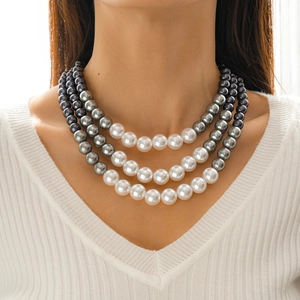 Detailed view of layered faux pearl necklace in white and grey gradients on model