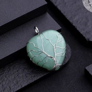 Macro shot of green heart-shaped stone pendant with silver Tree of Life wire wrapping