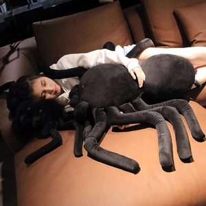 Large black spider plush toy held by a woman on a leather sofa for Halloween gift