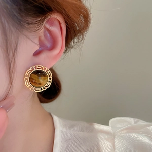 Close-up of retro golden geometric stud earring with brown tiger eye stone on model
