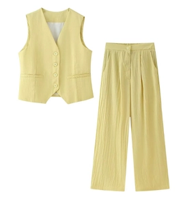Détail du gilet jaune clair à col en V et du pantalon large à texture verticale