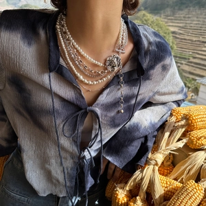 Multi-layer pearl and silver chain necklace featuring a lion head pendant on model