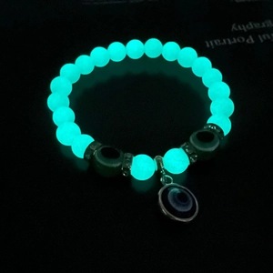 Detailed view of luminous beads and evil eye charms glowing green in the dark