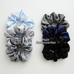 Close-up of satin silk scrunchies in blue and grey tones showing smooth texture