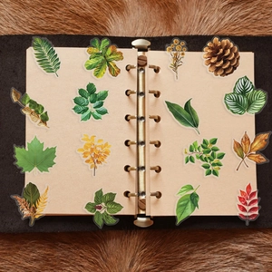 Detail of waterproof transparent PET botanical stickers on a vintage metal binder notebook