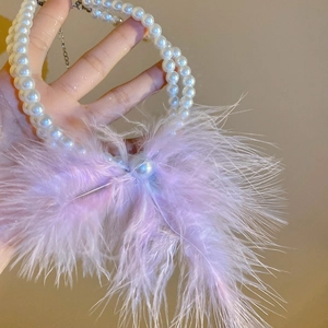 Macro detail of double-layer pearl necklace with purple feather and large central pearl