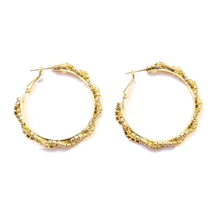 Macro shot of large golden hoop earrings with pavé white zircon and wavy edges