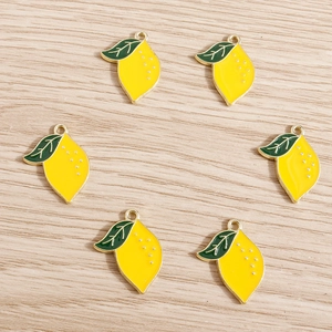 Macro shot of 6 yellow lemon fruit charms with gold metal edges on a light wood background