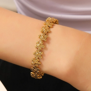 Close-up of a gold-plated bracelet featuring hollow floral patterns on a woman's wrist