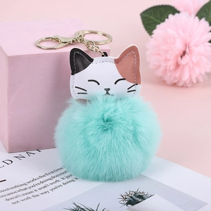 Detail of teal faux fur pom pom keychain with calico cat charm and gold hardware