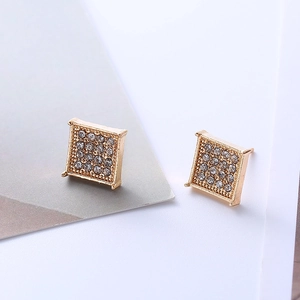 Macro shot of gold square stud earrings with micro-paved white zircons on a clean background