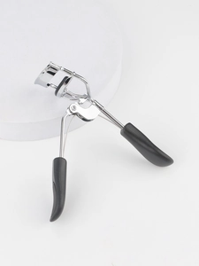 Detailed view of silver stainless steel eyelash curler with black ergonomic handle on pedestal