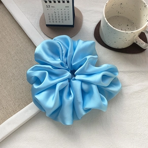 Detail of oversized sky blue satin scrunchie showing glossy silk texture and pleated folds
