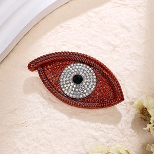 Detailed macro of red evil eye brooch with rhinestones and central black gemstone