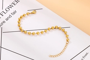 Macro shot of minimalist gold beaded bracelet with lobster clasp and extension chain
