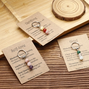 Detail of handmade natural stone keychains with healing crystal meaning cards on wood