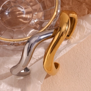 Detail of chunky wavy liquid style bangles in gold and silver mirror finish on paper