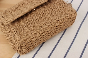 Detail of the woven straw bag featuring a secure metal magnetic clasp and textured pattern