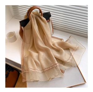 Close-up of beige silk wool blend scarf with elegant gold thread metallic trim details
