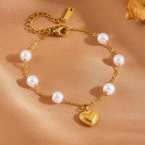 Détail d'un bracelet cœur en acier doré 18K avec perles sur fond de soie douce