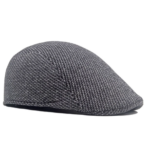 Detailed texture of gray herringbone wool fabric on a classic men's flat cap ivy hat