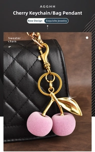 Detail of pink flocked cherry keychain with gold leaf on a black quilted leather bag