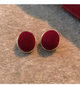 Detail of vintage burgundy velvet earrings with gold metal base on felt background