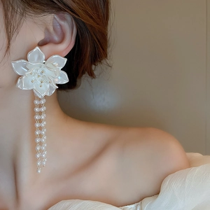 Dettaglio di orecchini a fiore con petali lucidi e nappe di perle a cascata