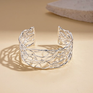 Macro detail of silver hollow intertwined texture on minimalist open cuff bracelet