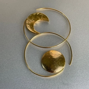 Detail of asymmetric gold sun and moon hoop earrings with handcrafted hammered texture