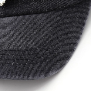 Macro shot of dark denim baseball cap brim featuring triple stitching and crystal inlay