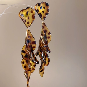 Macro view of leopard print acrylic petal earrings with flowing tassel design