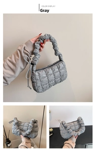 Detail of grey quilted puffy handbag with scrunchie handle and metallic zipper finish