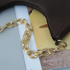 Close-up of chocolate leather shoulder bag with chunky gold chain strap and luxury texture